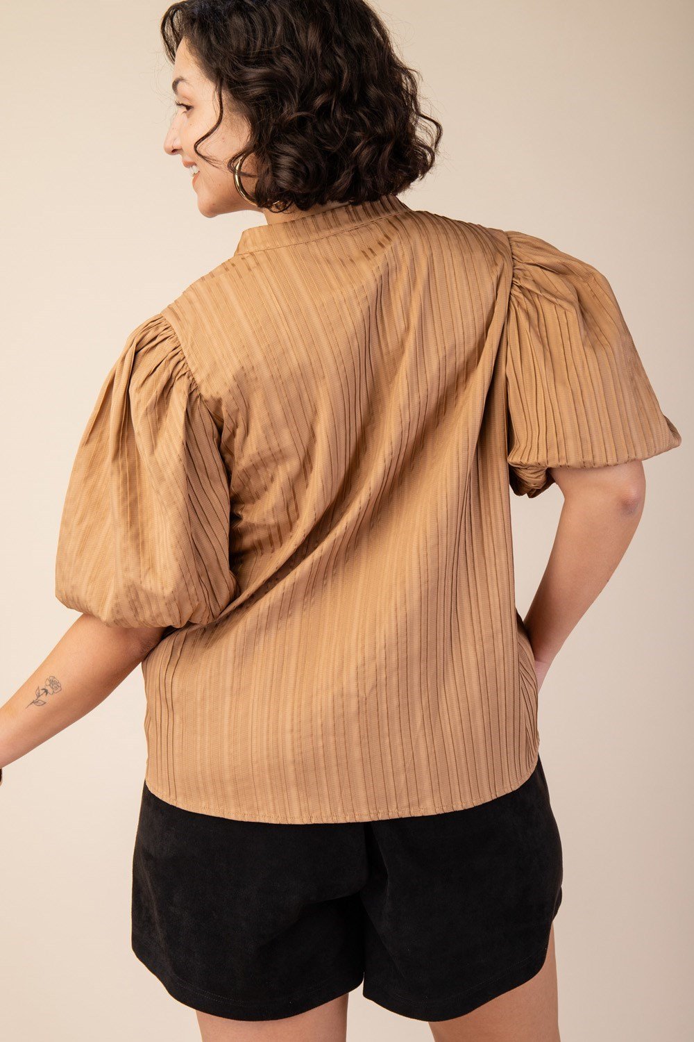 Curvy plus size woman in a taupe textured satin top, showcasing stylish coastal boutique clothing for tropical vacations.