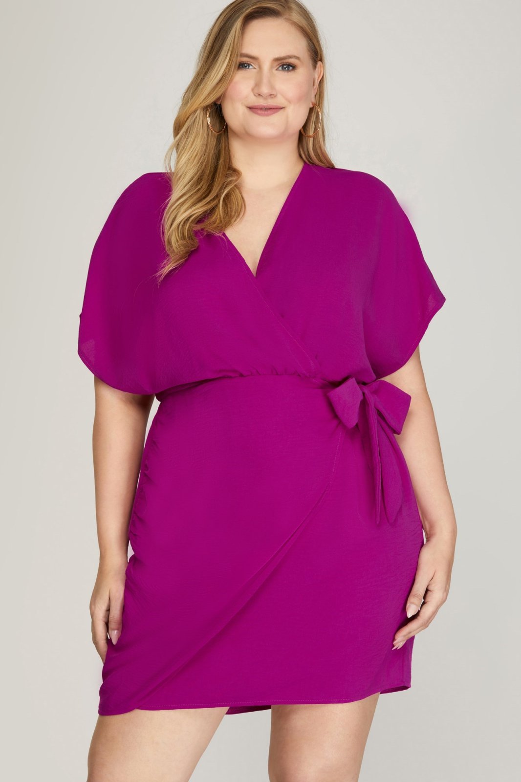 Curvy plus size fashion in a vibrant magenta dolman sleeve dress, perfect for tropical vacations and casual beach outings.