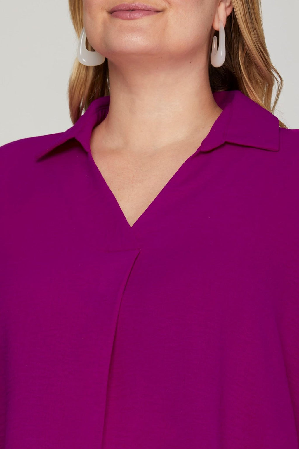 Close-up of a woman in a magenta collared woven top, showcasing curvy plus size fashion from a coastal boutique.