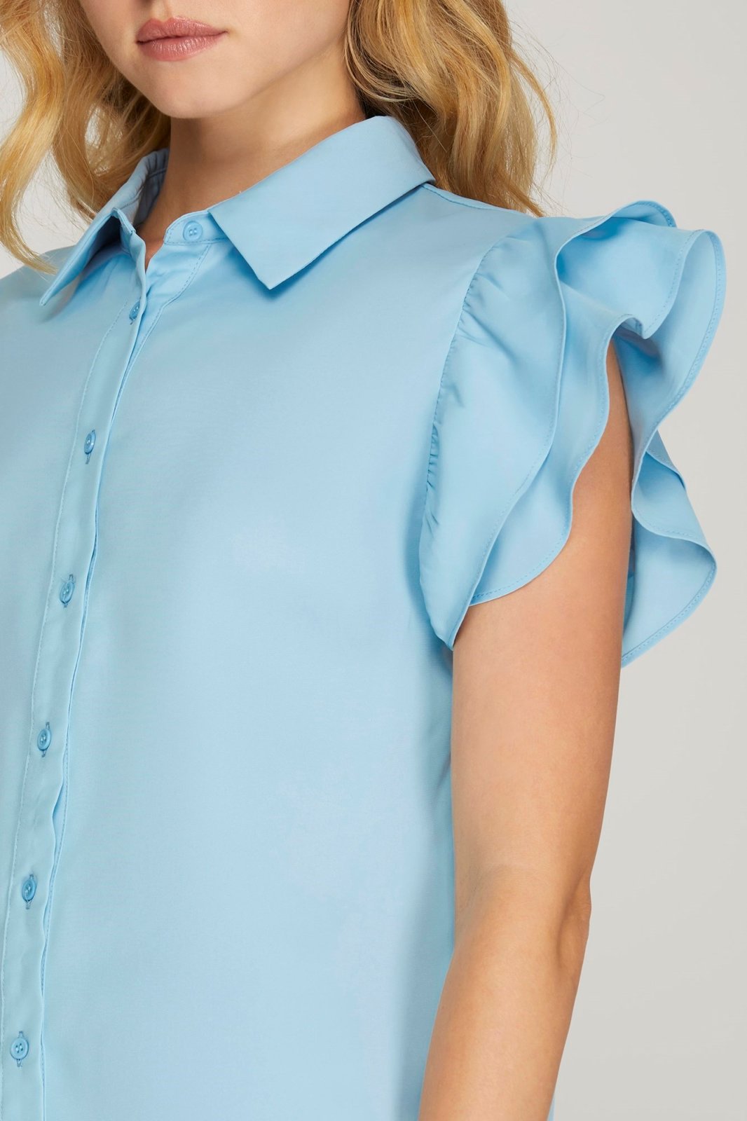 Sky blue top with flutter sleeves, perfect for coastal boutique clothing. Stylish addition to beach dresses and curated women's fashion.