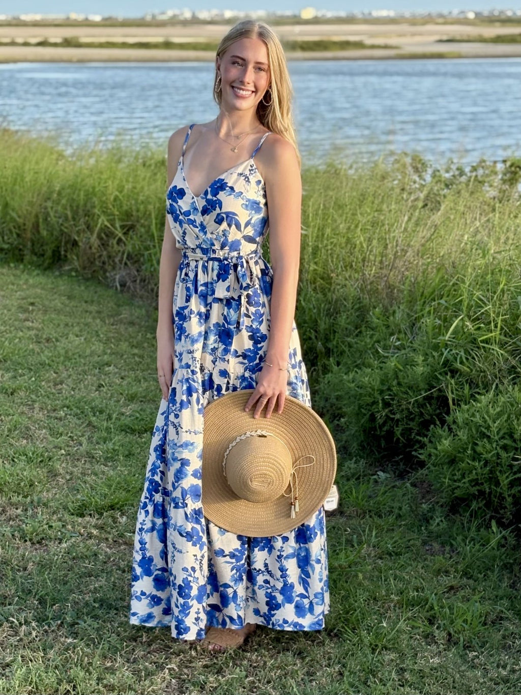 Woman in a blue floral maxi dress with a straw hat, perfect for coastal boutique clothing and tropical vacation dresses.