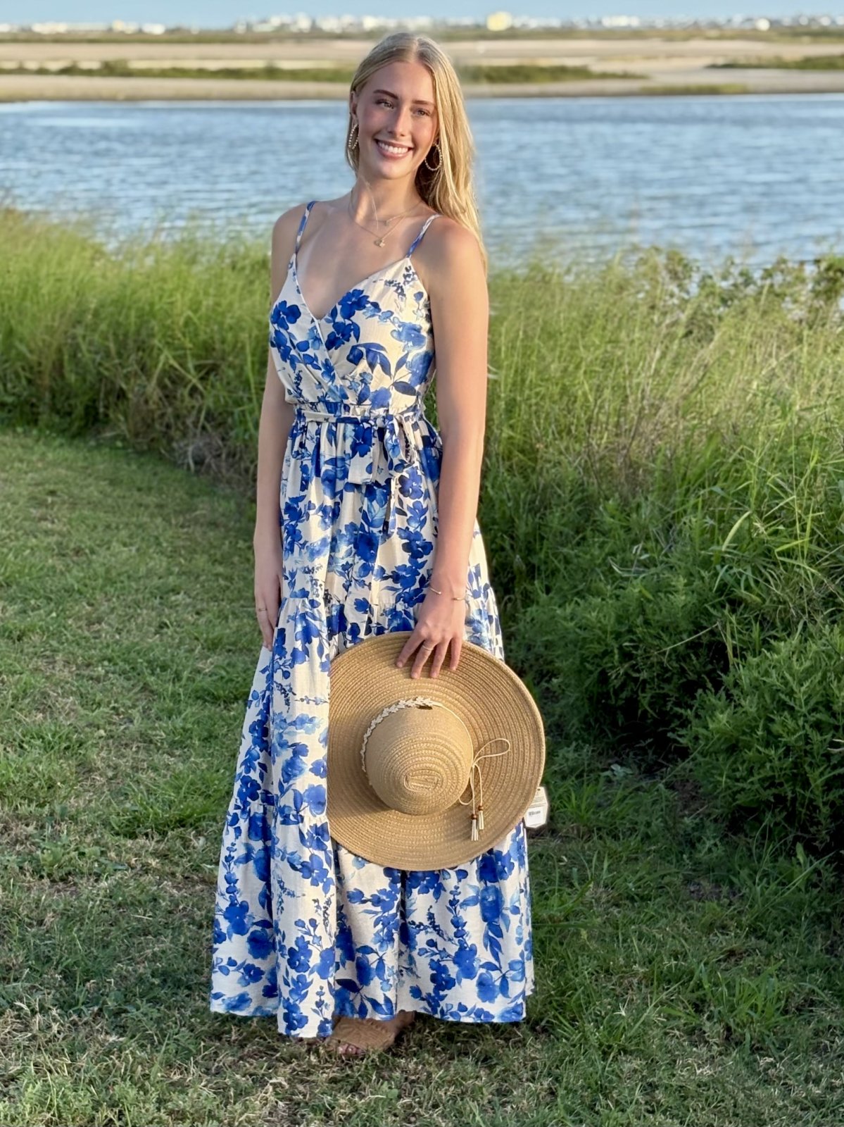 Woman in a blue floral maxi dress with a straw hat, perfect for coastal boutique clothing and tropical vacation dresses.