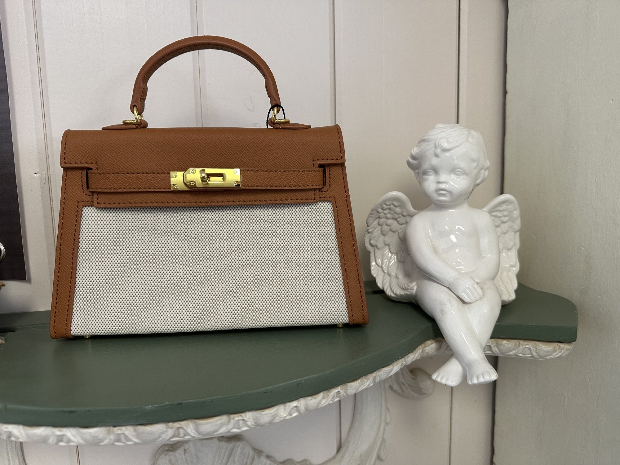 Laura Bag displayed beside an angel statue, showcasing curated women's fashion at a Port Aransas boutique.
