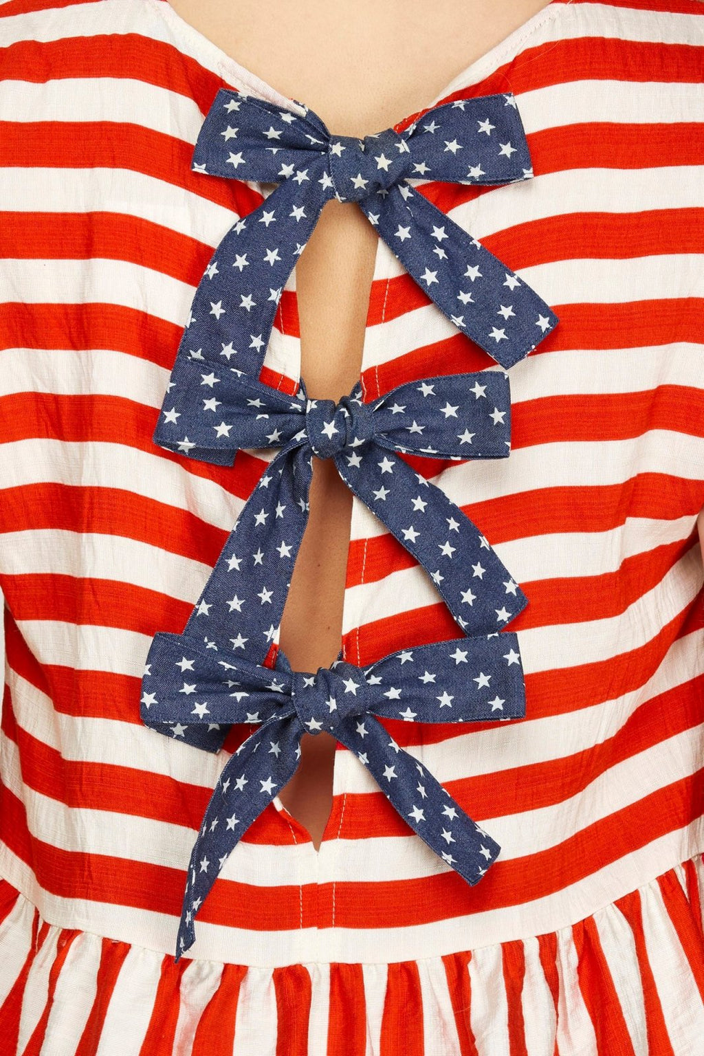 Back view of striped Celebration Top with contrasting blue star-patterned bows, perfect for coastal boutique clothing.