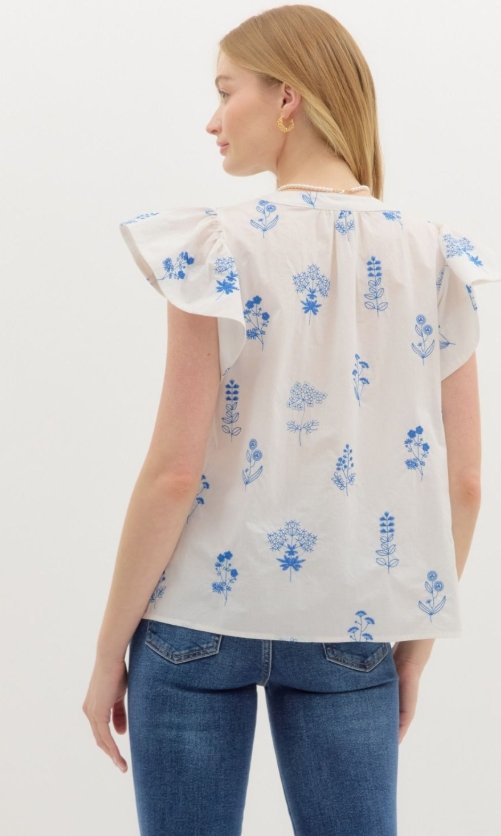 Model showcasing the Scarlet Top in Blue with floral print and flutter sleeves, perfect for summer outfits Texas.