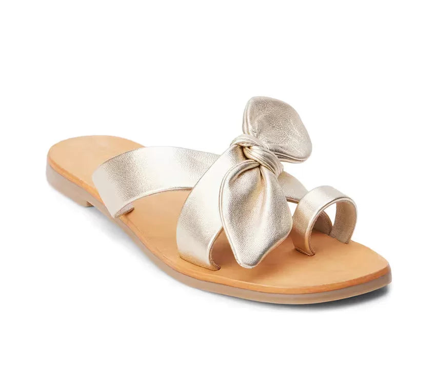 GOLD VAUGHN SLIDE SANDALS BY MATISSE with crisscross straps and bow accents for trendy coastal style.