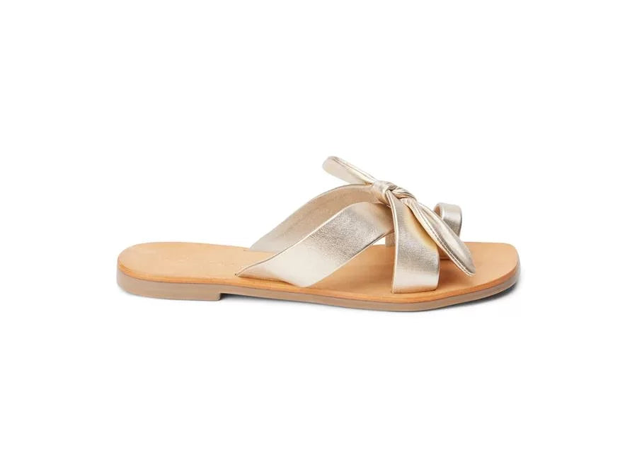 GOLD VAUGHN SLIDE SANDALS BY MATISSE with crisscross straps and bow accents, perfect for trendy coastal style.