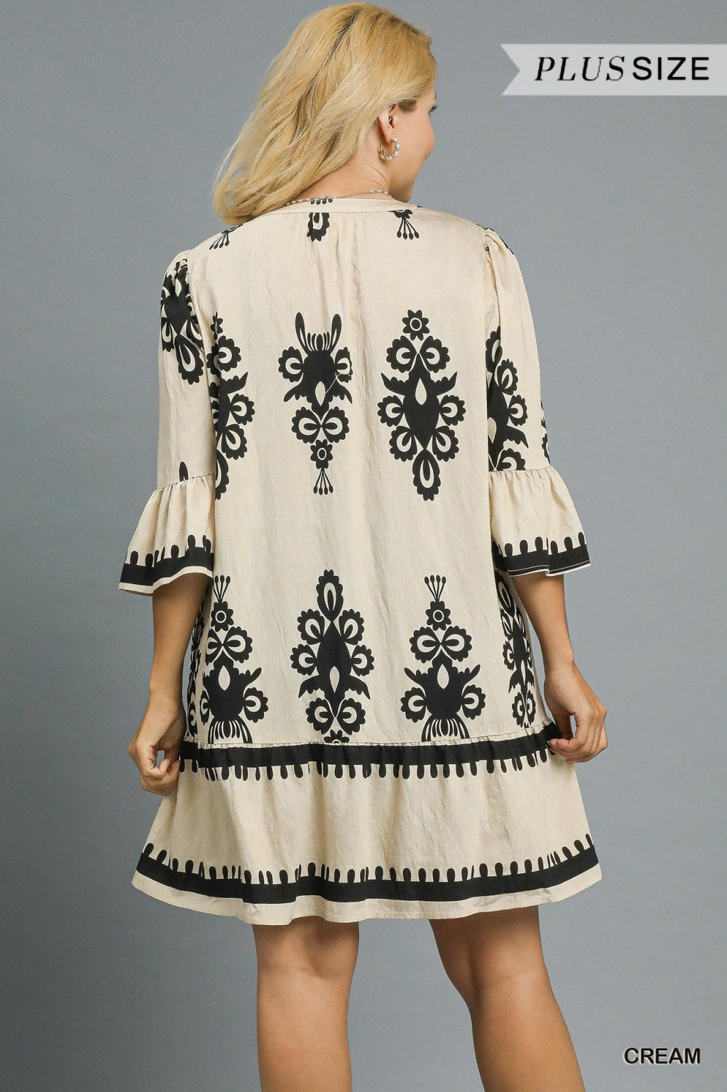 Plus size cream mini dress with black border print, featuring ruffle sleeves and a feminine silhouette, perfect for beach outings.