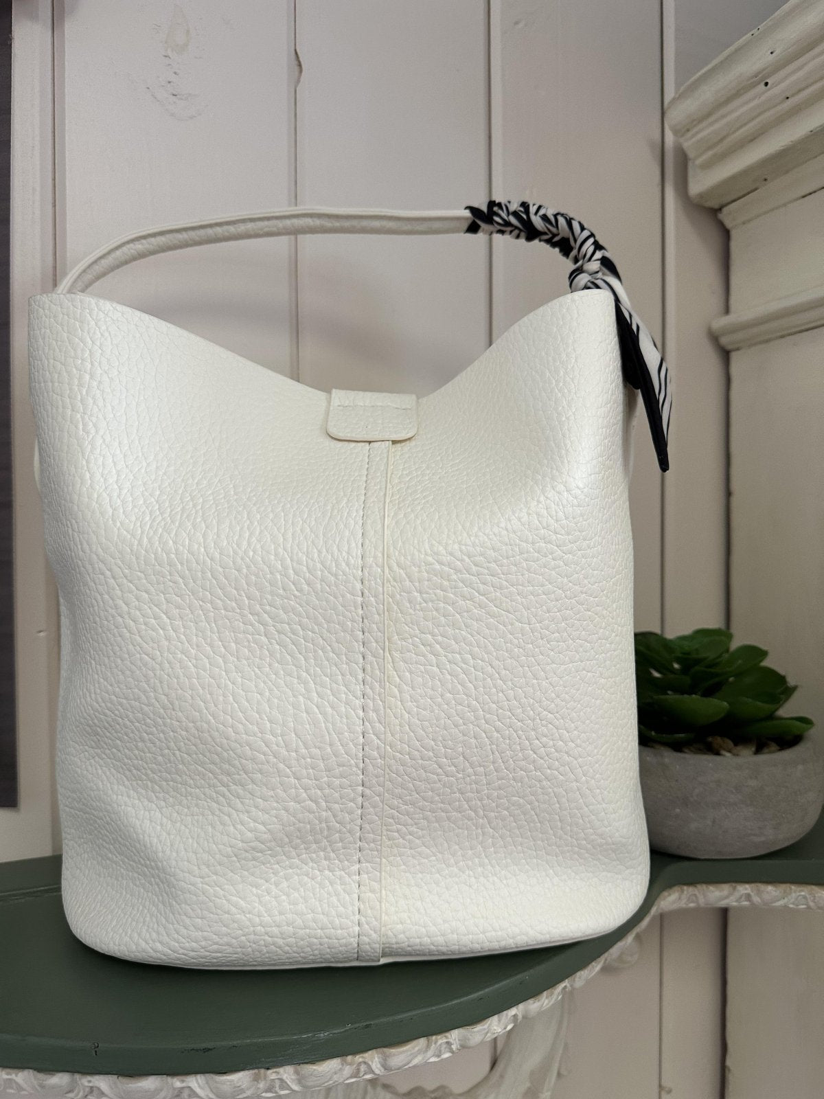 Stylish white handbag with a striped handle, perfect for coastal boutique clothing and fashionable gifts.