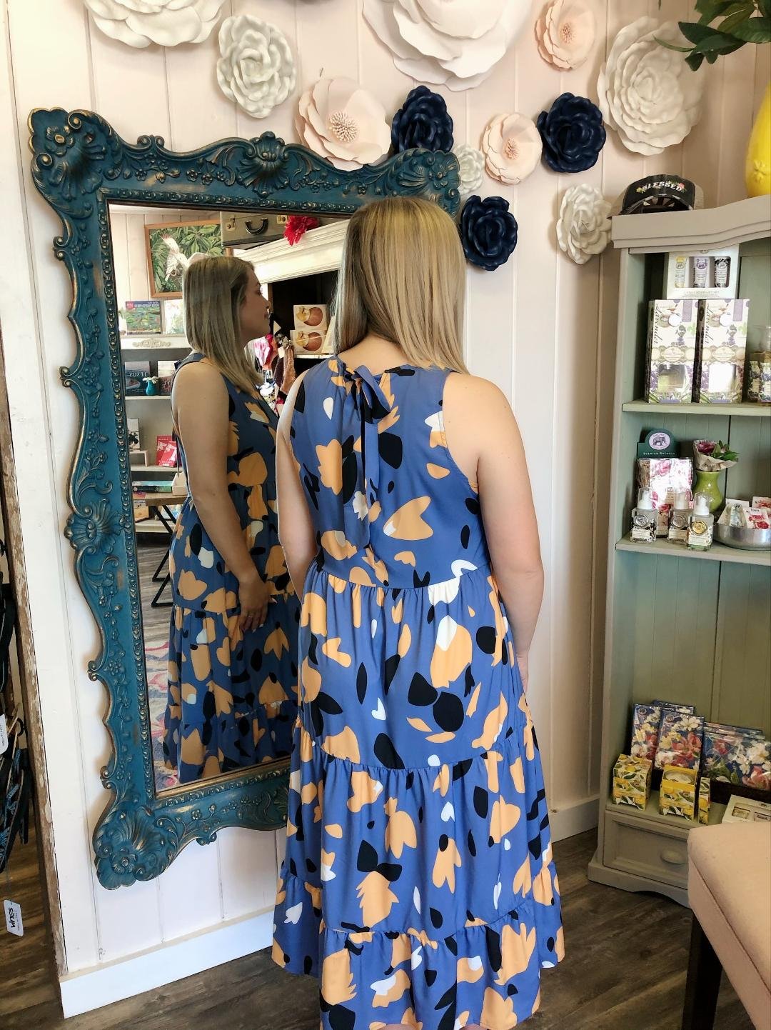Blue print midi dress with back bow displayed in a mirror, showcasing curvy plus size fashion from a coastal boutique.