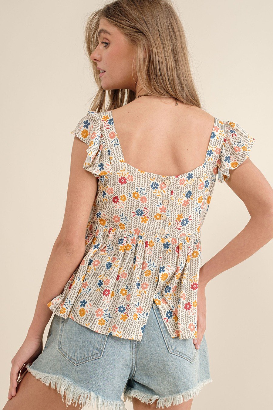 Floral ruffle Calla Top, perfect for coastal boutiques, styled with shorts for a romantic beach look.