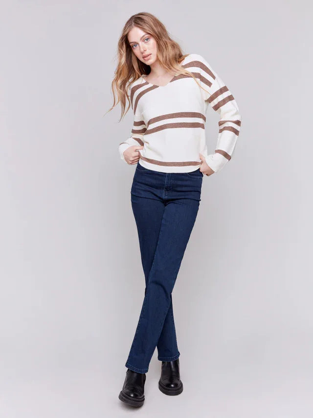 Ecru-striped V-neck sweater styled with blue jeans, perfect for coastal boutique clothing and curated women's fashion.