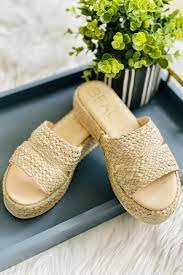 LAYBACK NATURAL RAFFIA SLIDE on a blue tray with a potted plant, perfect for coastal fashion from Raggdoll Boutique.