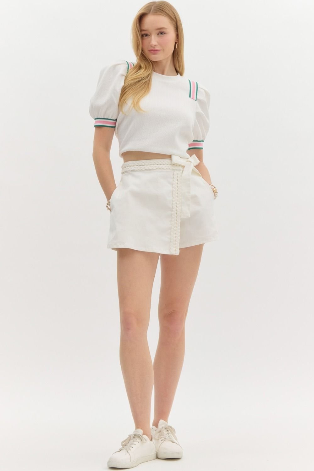 Model wearing the cutest white skort with braided waist detail, perfect for summer beach outfits from a coastal boutique.