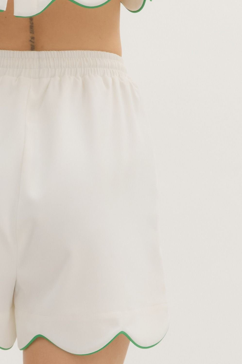 Stylish scalloped hem shorts in white with green trim, perfect for coastal boutique clothing and beach dresses.