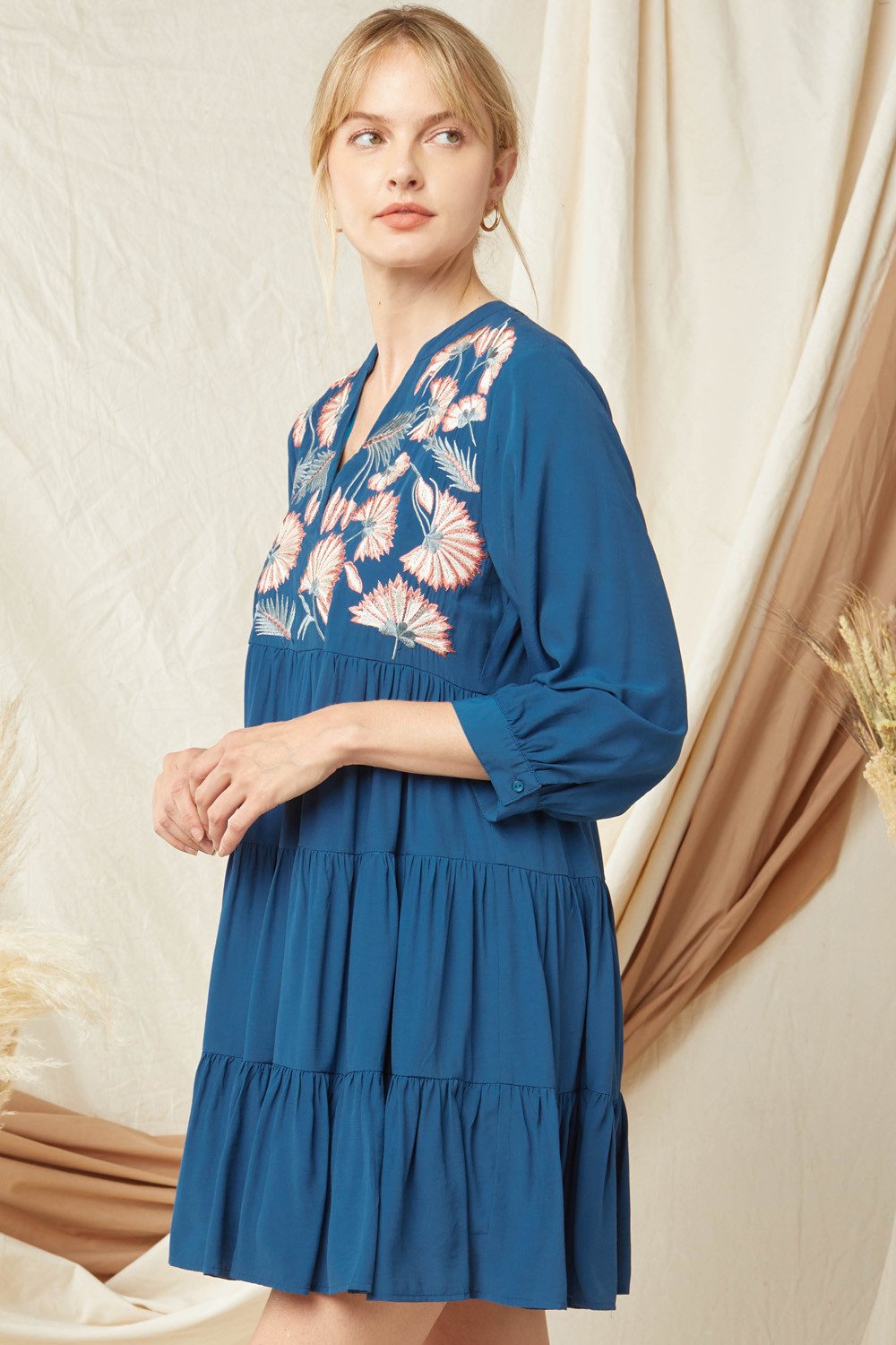 Wearing PERFECT TEAL EMBROIDERED DRESS from Raggdoll Boutique, featuring floral embroidery and a tiered design.