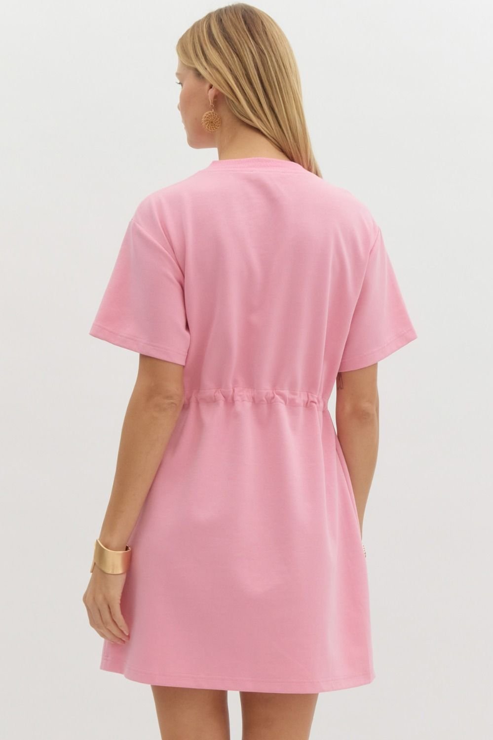 Woman wearing a pink Bailey Dress from a coastal boutique, perfect for beach outings and tropical vacations.