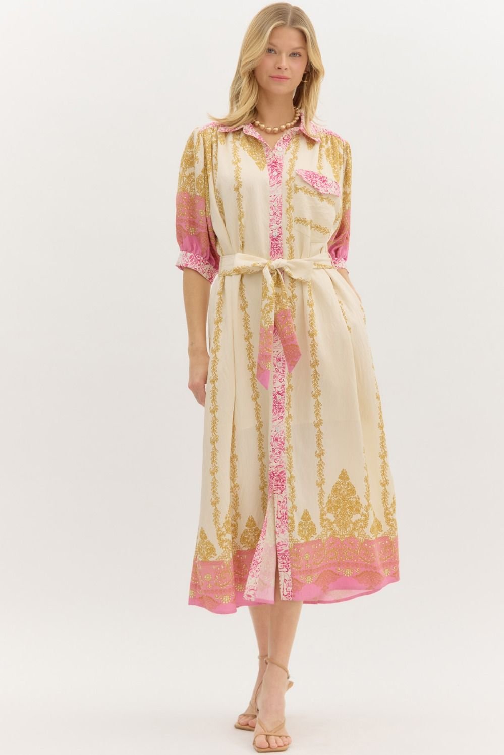 Chic pink border-accent midi dress with ¾ sleeves, perfect for a tropical vacation and essential at a coastal boutique.
