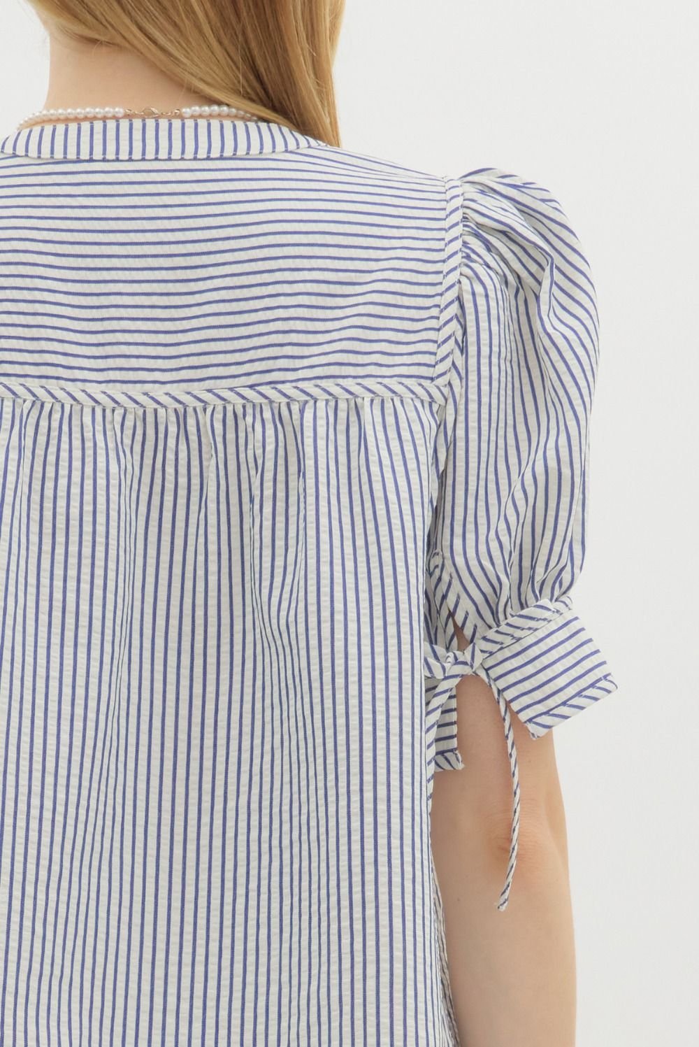 Back view of blue striped structured top with bow tie cuffs, ideal for coastal boutique clothing and stylish women's fashion.