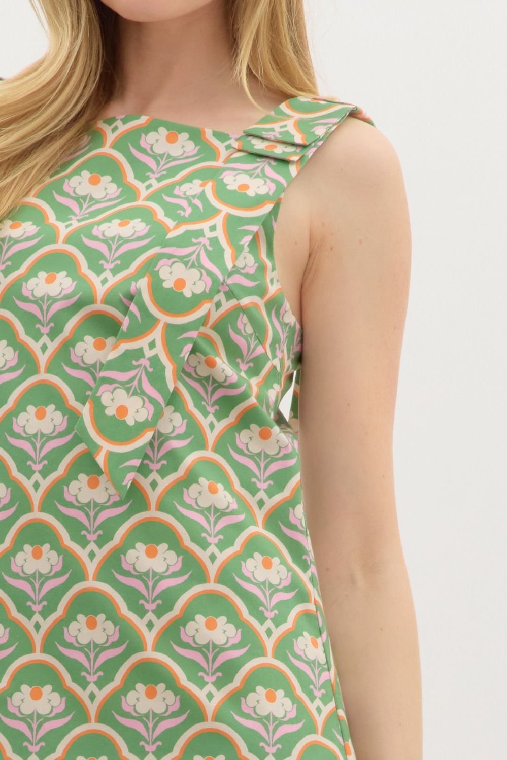 Close-up of stylish green mini dress with floral scallop motif, perfect for coastal boutique clothing and tropical vacations.