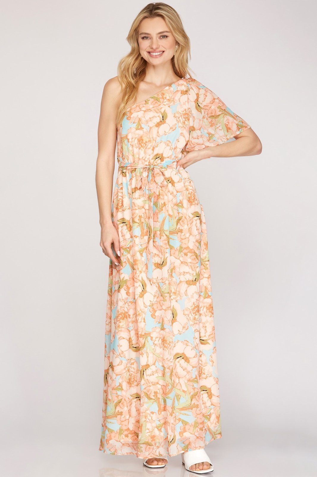 PEACHES N' CREME DRESS model wearing a one shoulder woven maxi dress with half flutter sleeve from Raggdoll Boutique.