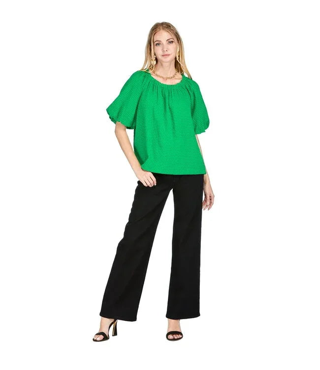 Embellished green top from a coastal boutique, featuring puff sleeves and a bow tie, perfect for tropical vacation outfits.