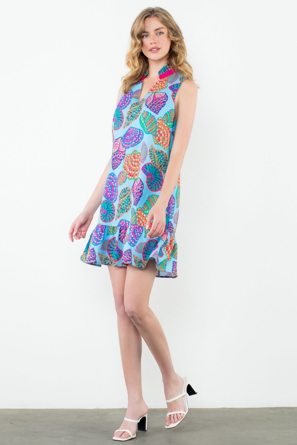 Vibrant shell print sleeveless dress with ruffle hem, perfect for beach vacations and coastal boutique clothing.