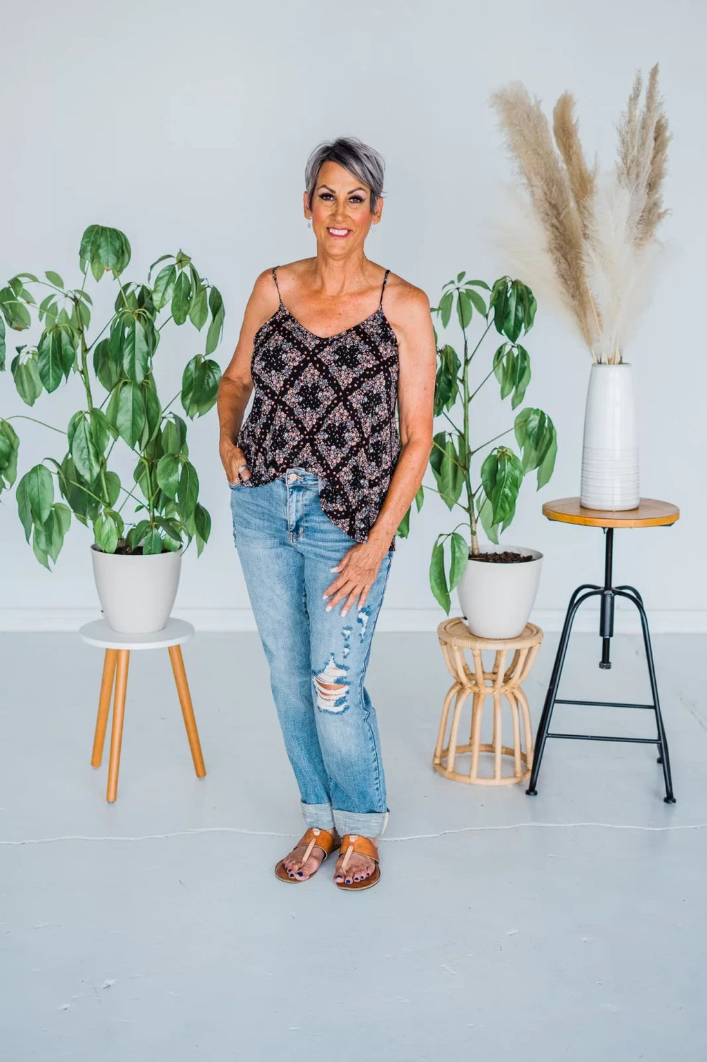 Woman in stylish top and boyfriend jeans from a coastal boutique, surrounded by greenery, perfect for casual outings.