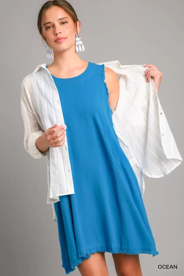 Model showcasing OCEAN BLUE DRESS with ruffle hem paired with a white shirt at Raggdoll Boutique.