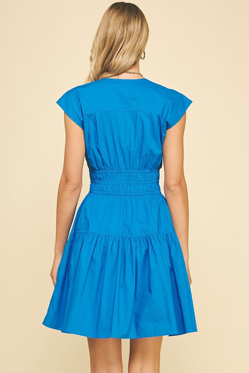 Vibrant blue Karlie Dress featuring cap sleeves and a smocked waist, perfect for coastal boutique clothing and beach dresses.
