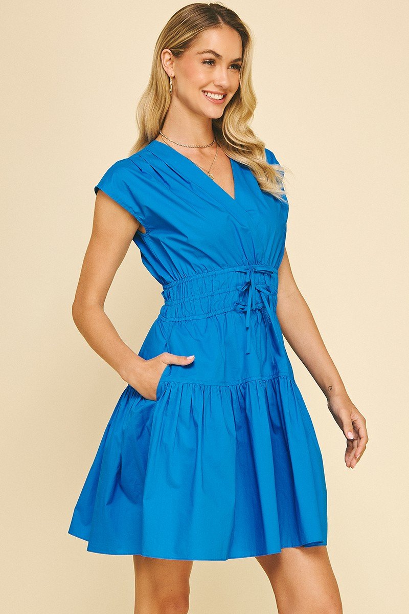 Vibrant blue Karlie dress with V-neck, cap sleeves, smocked waist, pockets, perfect for coastal boutique clothing and summer style.