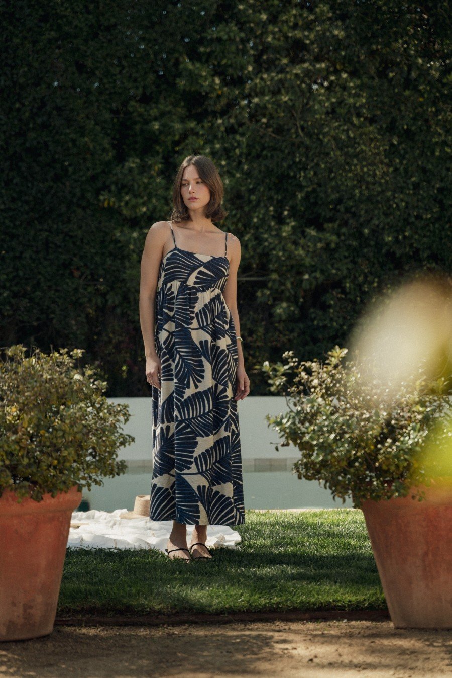 Model showcasing a stylish spaghetti strap maxi dress with a leaf print, perfect for summer beach outings or garden parties.