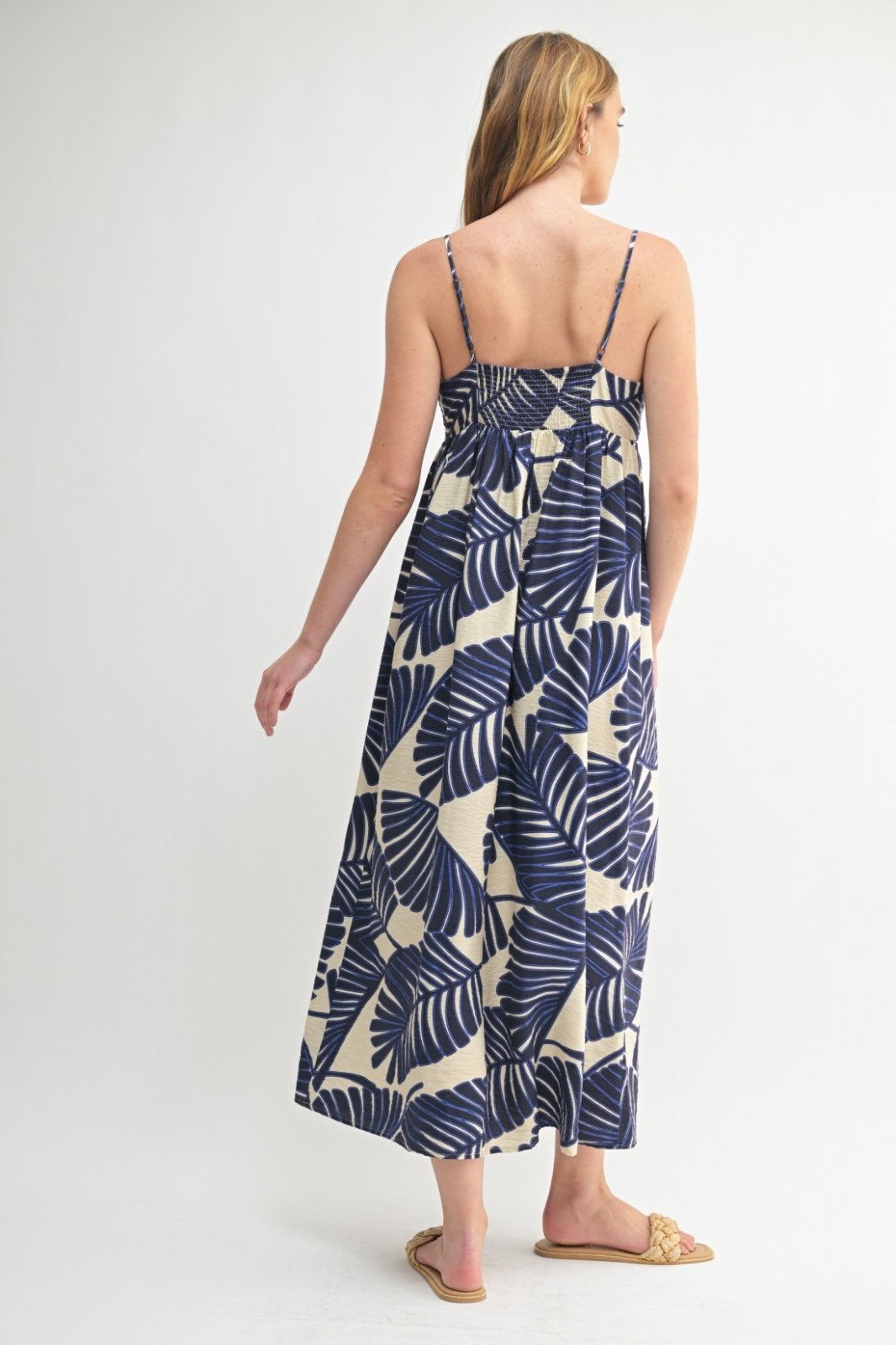Back view of a woman in a blue and cream floral maxi dress from a coastal boutique, perfect for summer events.
