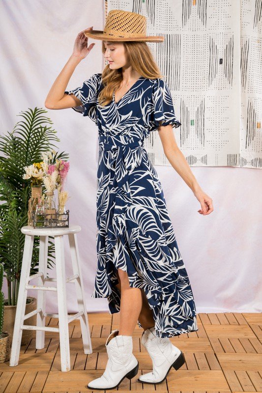 Model wearing SUN KISSED MIDI IN NAVY dress with tropical leaf print, showcasing trendy coastal style at Raggdoll Boutique.
