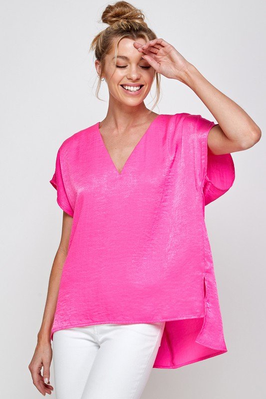 FUSHIA SATIN V-NECK TOP modeled by a smiling woman in pink, showcasing trendy coastal style from Raggdoll Boutique.