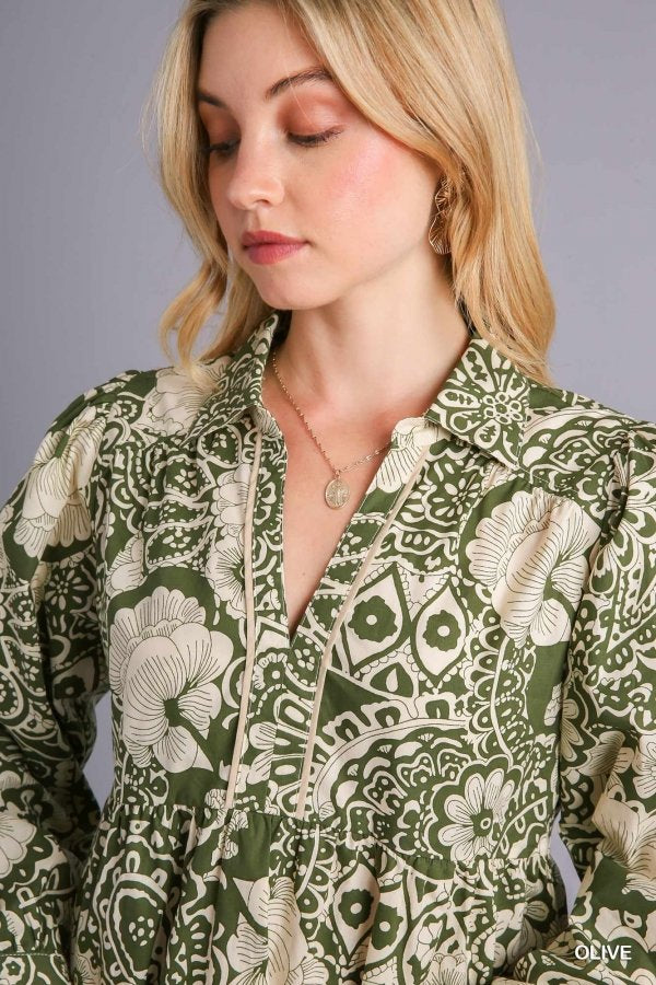 Woman wearing an olive mixed print babydoll top from a coastal boutique clothing collection, perfect for beach outfits.