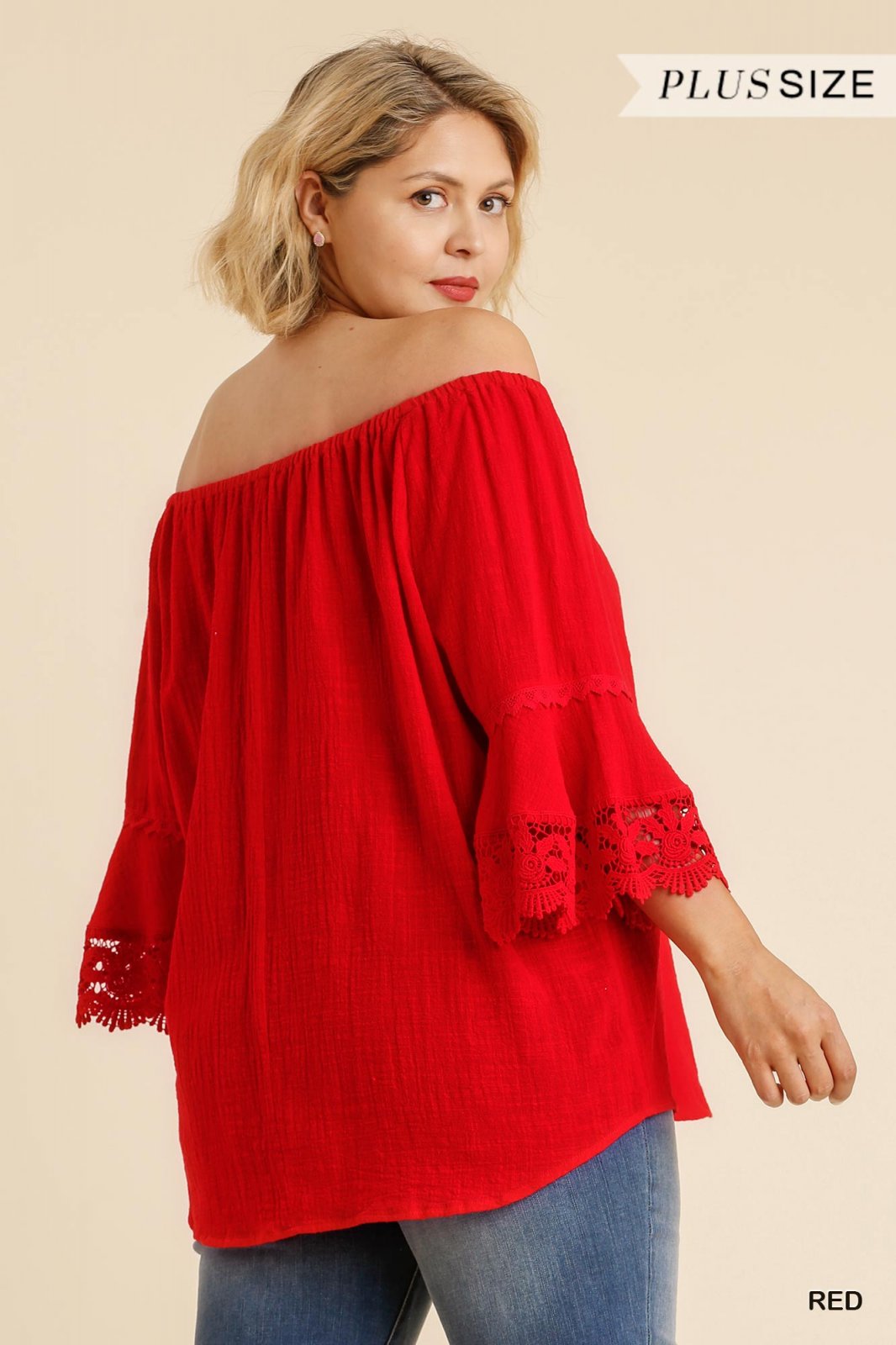 Curvy woman in red off-shoulder lace trimmed plus top, showcasing stylish beach boutique fashion for tropical vacations.