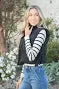 Trendy black cropped vest with bow side details, paired with stylish striped top, perfect for coastal boutique clothing.