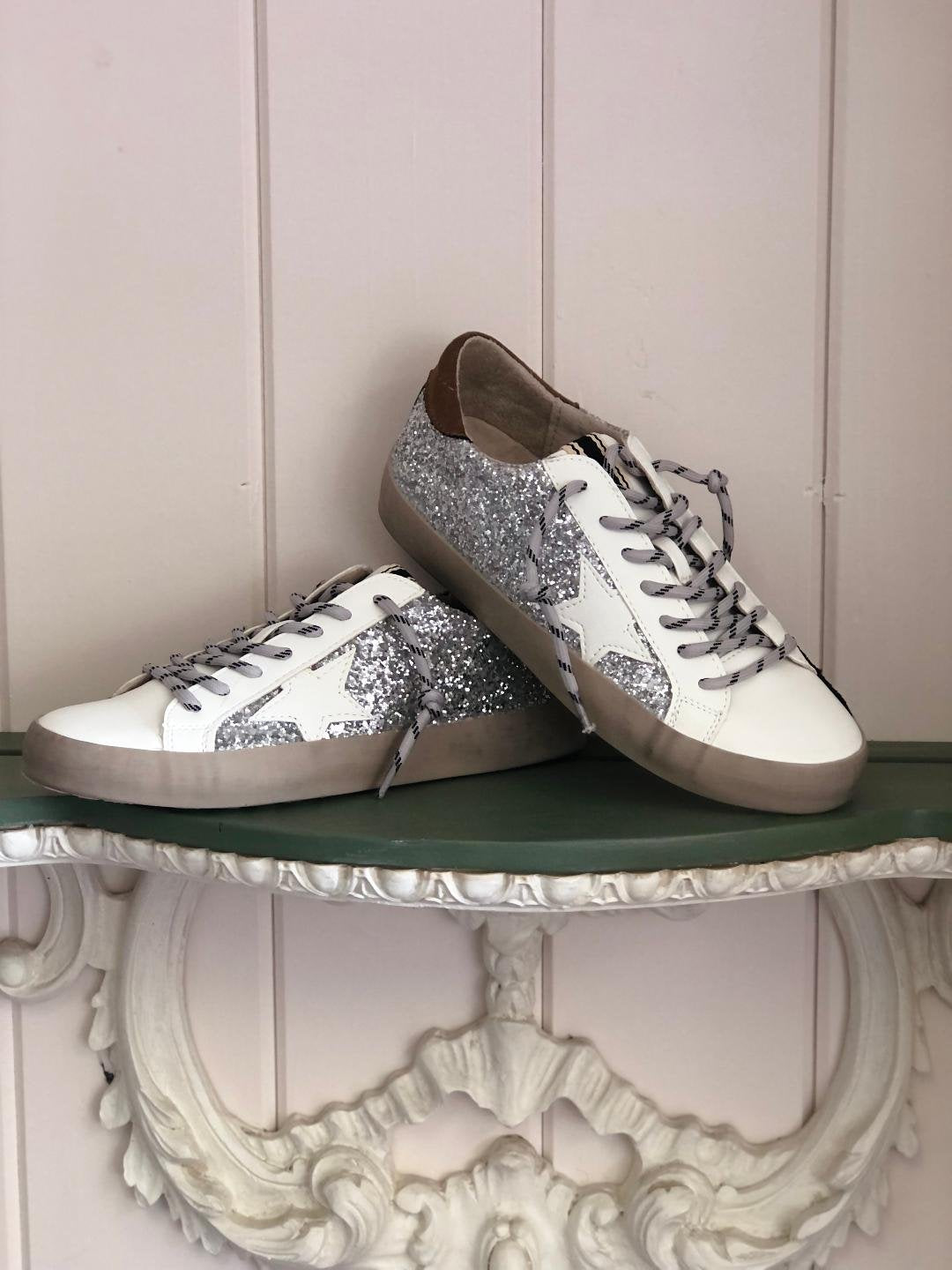 PAULA SILVER SPARKLE SNEAKER displayed on a decorative surface, perfect for trendy coastal style outfits from Raggdoll Boutique.