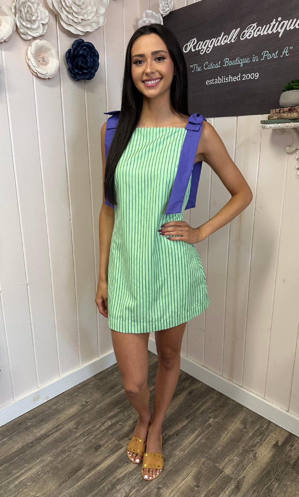 Libby Dress at Raggdoll Boutique, showcasing a green striped design with purple bow straps, perfect for summer outfits in Port Aransas.