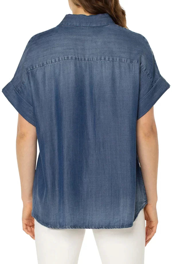 Back view of the LIVERPOOL DENIM CAMP SHIRT in denim, showcasing short sleeves and hi-low hem from Raggdoll Boutique.