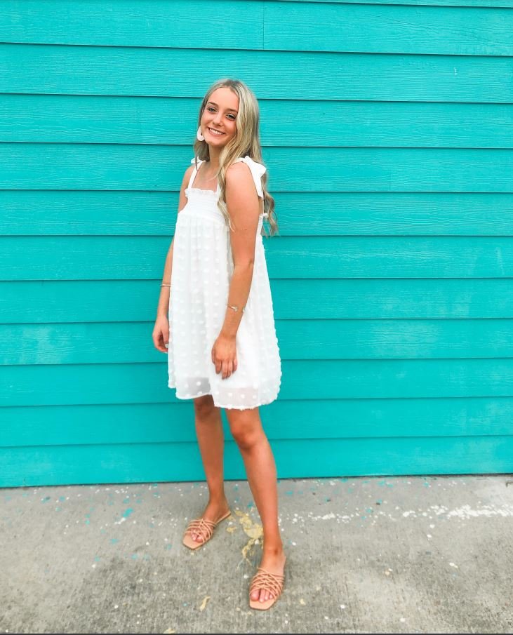 A model wearing a WHITE DOT DRESS from Raggdoll Boutique, perfect for trendy coastal style and summer outfits.