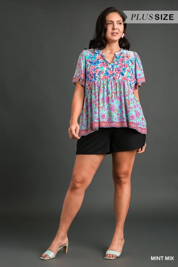 Plus size woman wearing a colorful top with floral pattern, showcasing MINT FLORAL MIX from Raggdoll Boutique.