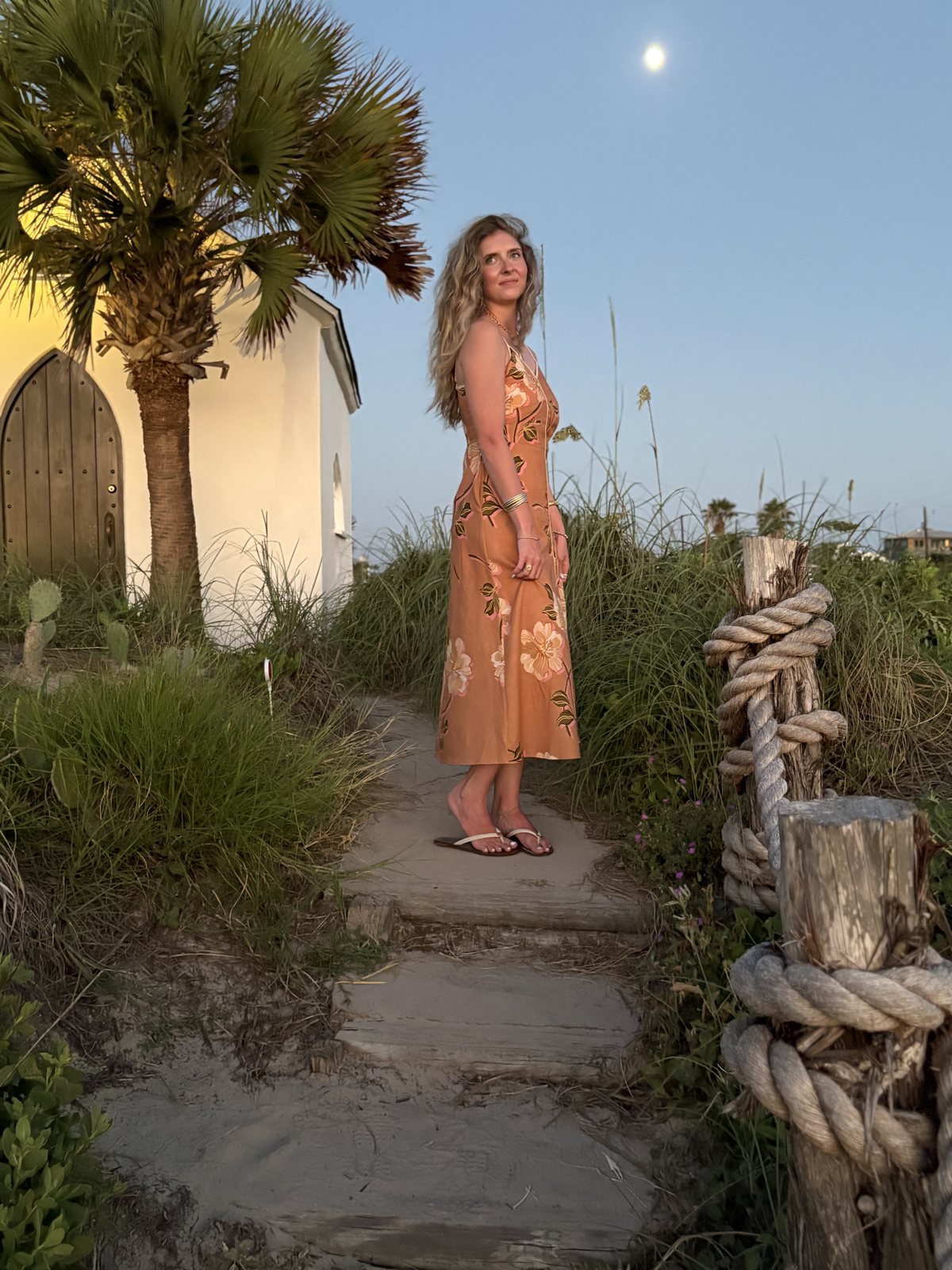 Woman wearing a peach floral dress near the beach