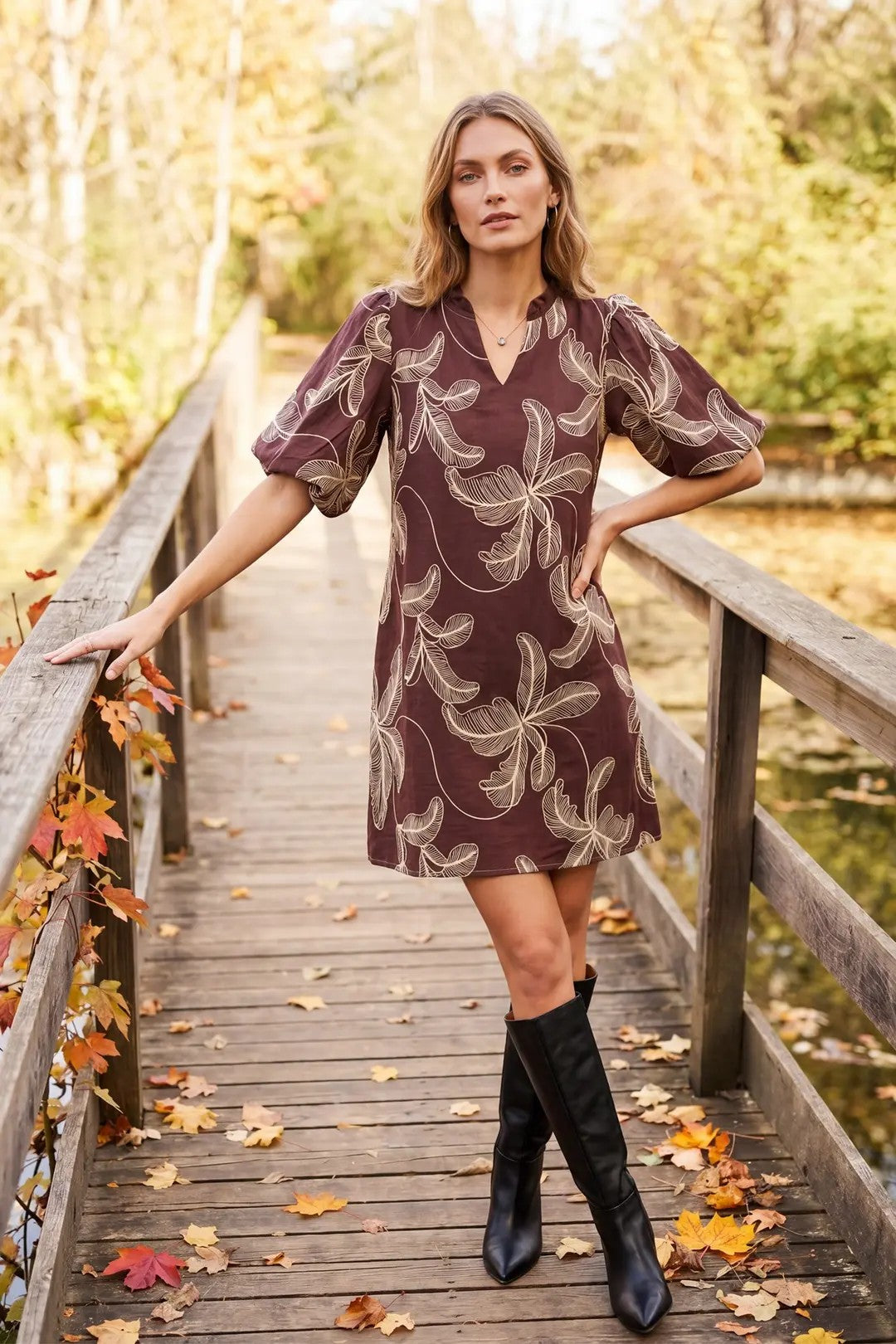 Model wearing a brown floral dress on a wooden bridge